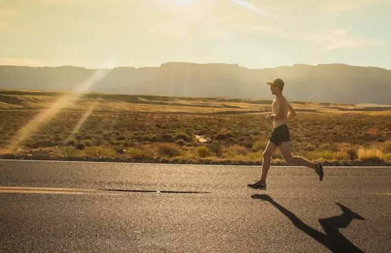 Runner on road in desert.