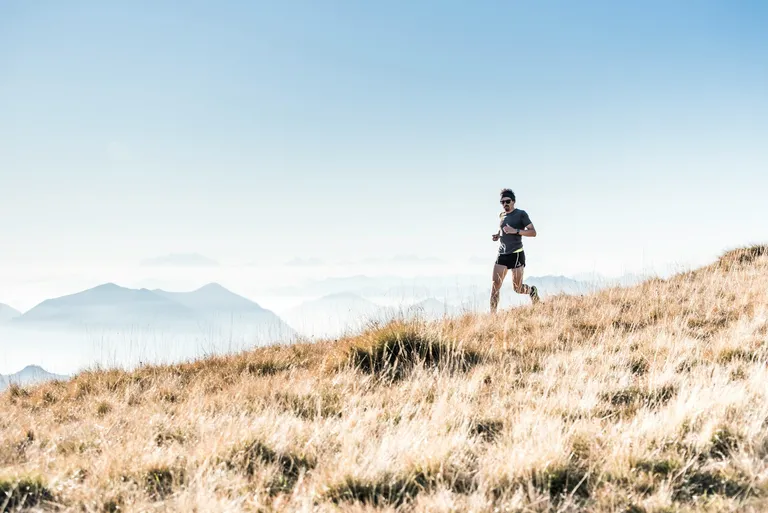 Man running down grassy hill.
