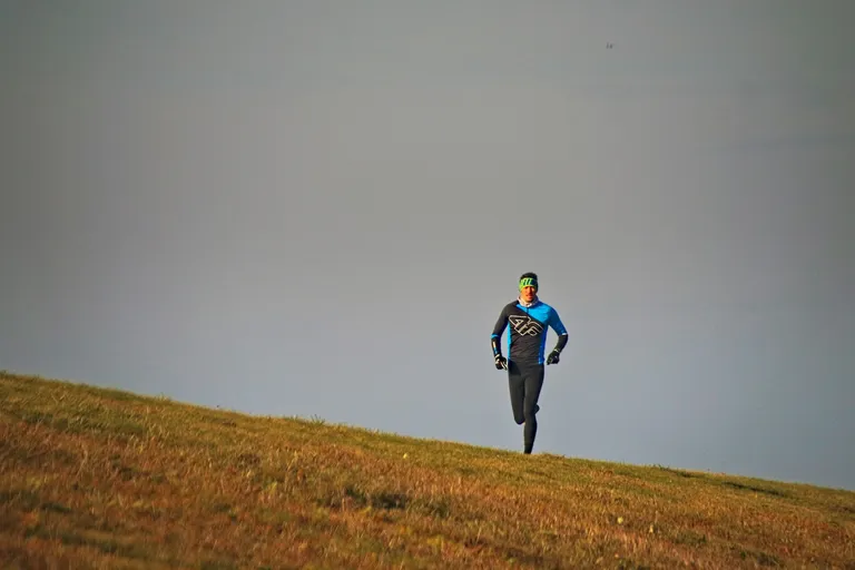 Man running on grassy hill.