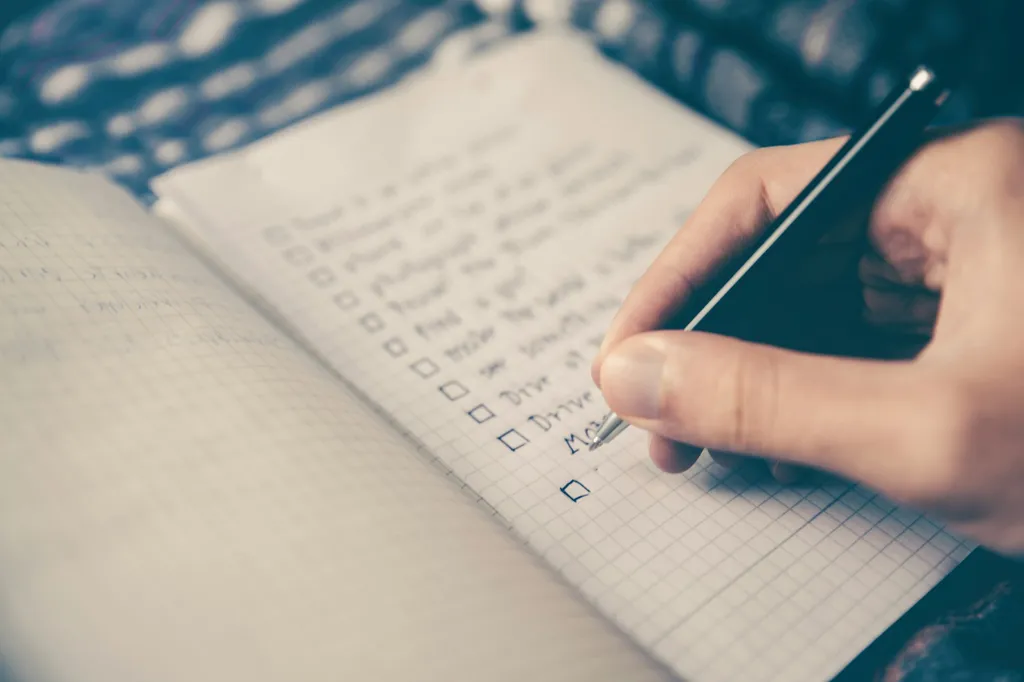 A hand writing on a piece of paper with a pen.