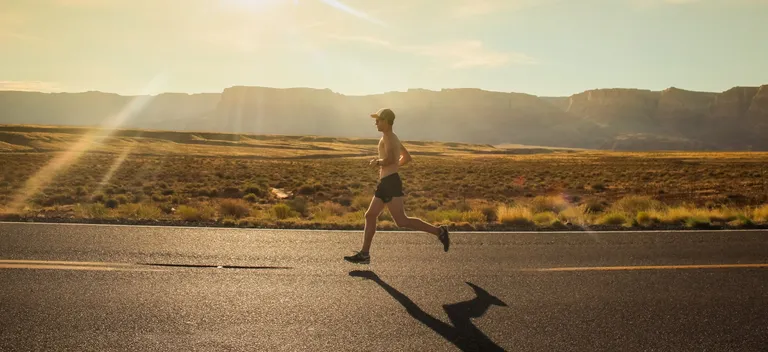 Runner on road in desert.