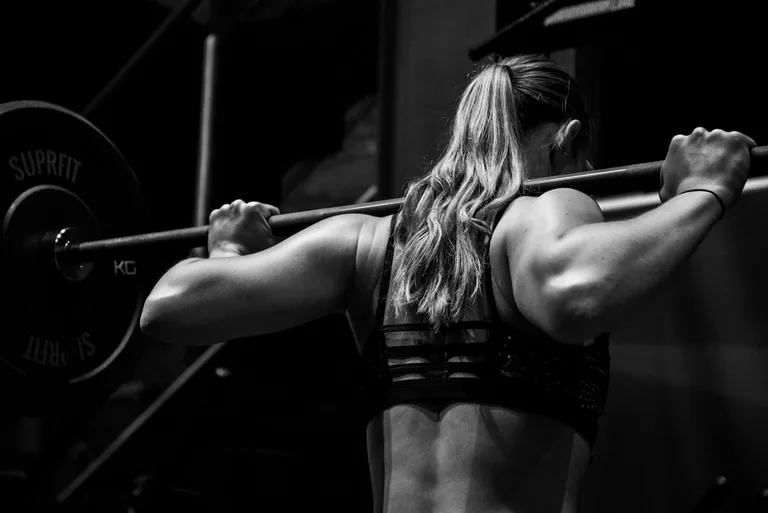 Woman performing barbell squat.